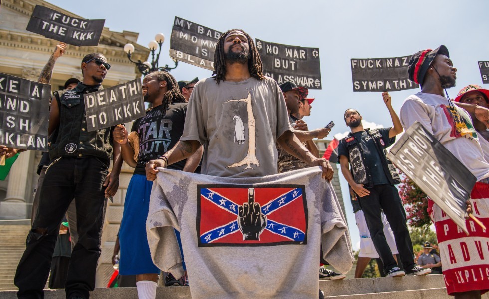 Columbia, United States. 18th July 2015 -- A counter-protester holds an anti-Confederate flag sweatshirt during the rally at the South Carolina Statehouse. -- The white supremacist Ku Klux Klan held a rally at the South Carolina Statehouse to protest the removal of the Confederate flag from the Capitol grounds. Hundreds of counter-protesters were at the rally and shouted angrily at Klan members.