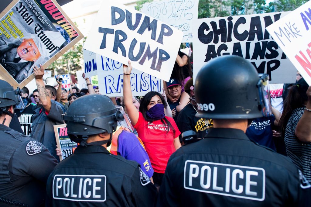 Police form a line to contain protesters outside a campaign rally for Republican presidential candidate Donald Trump on Thursday, June 2, 2016, in San Jose, Calif. A group of protesters attacked Trump supporters who were leaving the presidential candidate's rally in San Jose on Thursday night. A dozen or more people were punched, at least one person was pelted with an egg and Trump hats grabbed from supporters were set on fire on the ground. (AP Photo/Noah Berger)