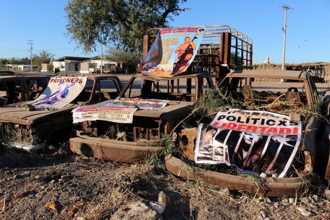 Three burned vehicles with banners on them calling for the freedom of Fidencio Aldama.
